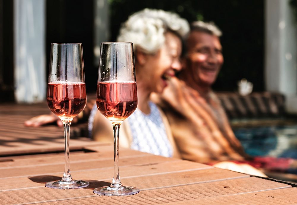 Happy seniors drinking prosecco in the pool