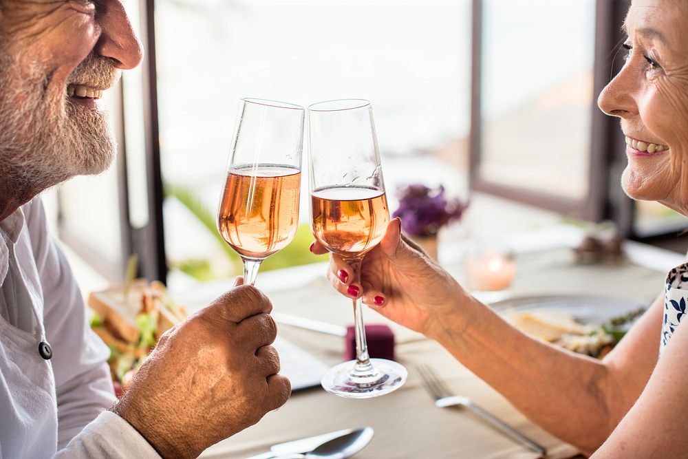 Cheerful senior couple drinking rose champagne