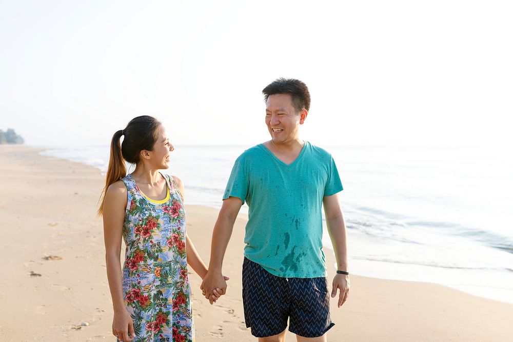 Asian couple holding hands at the beach