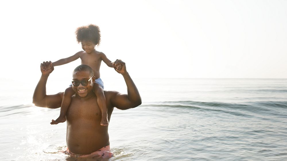 African American dad and son playing piggyback in the sea design space