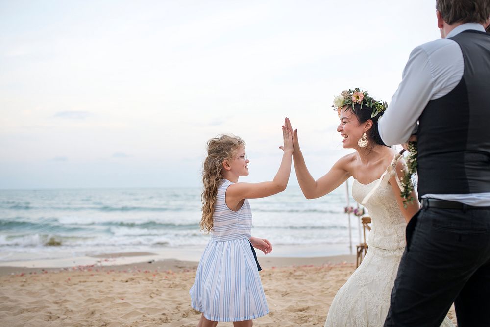 Bride giving a girl a high five at the beach wedding