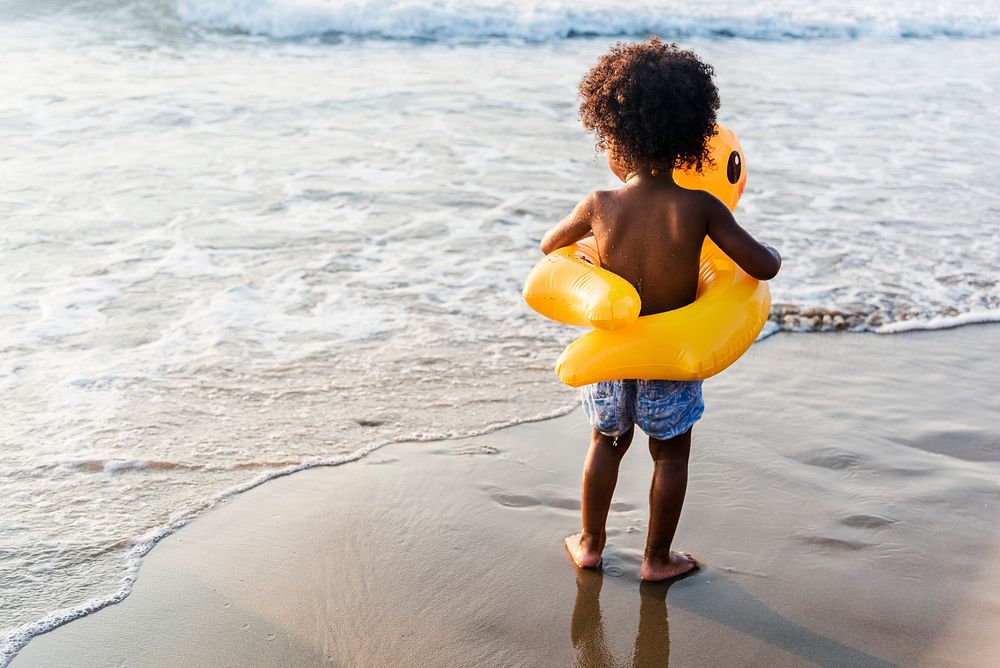 Cute toddler with duck tube on the beach