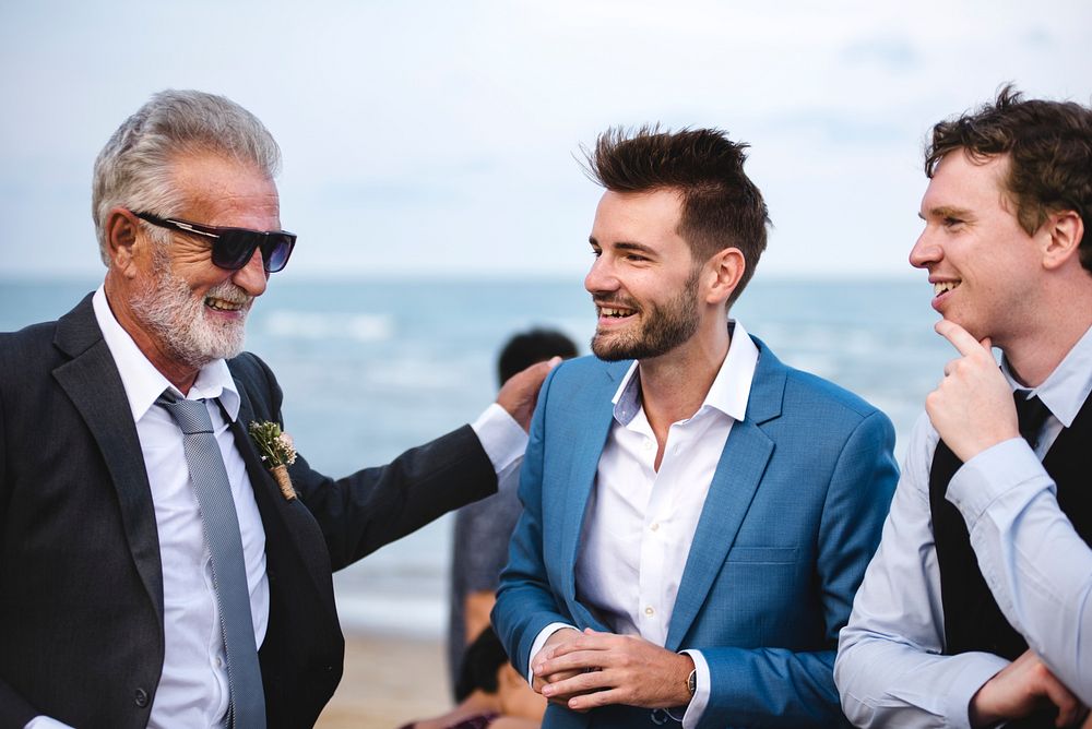 Men talking at a beach wedding