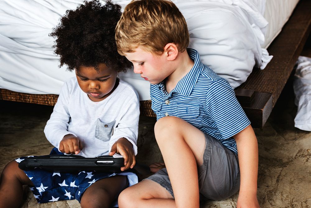 Friends playing with tablet in bedroom