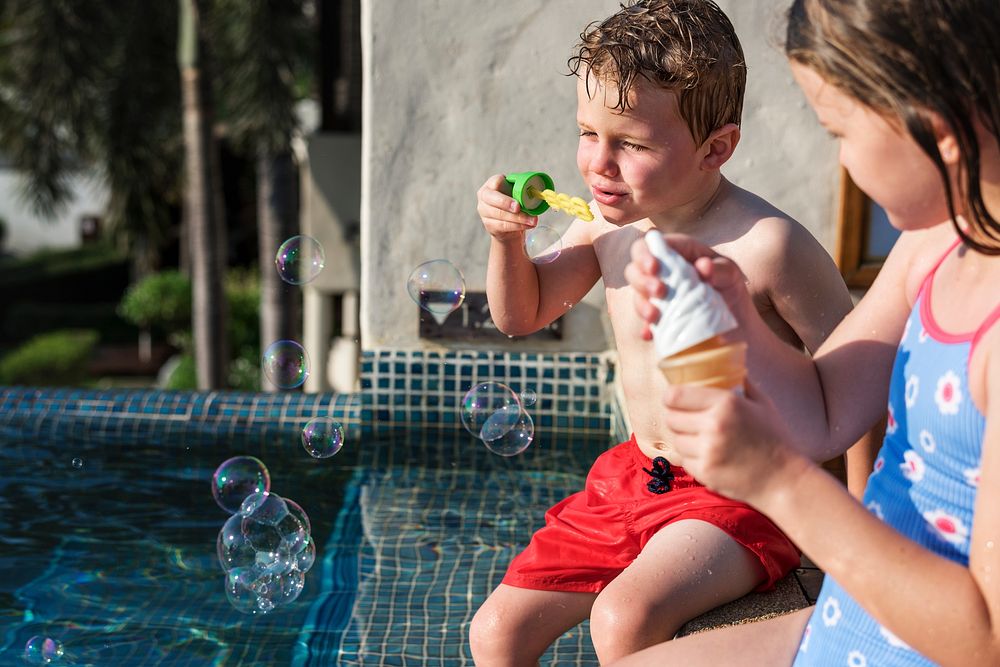 Kids blowing bubbles by swimming pool