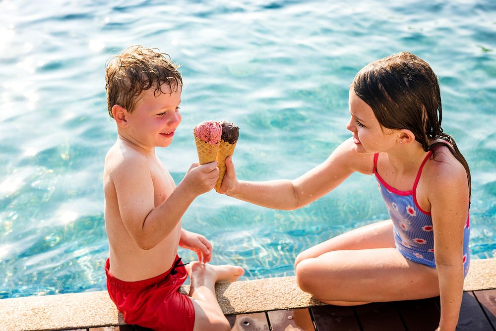 Kids toasting with ice creams at the poolside