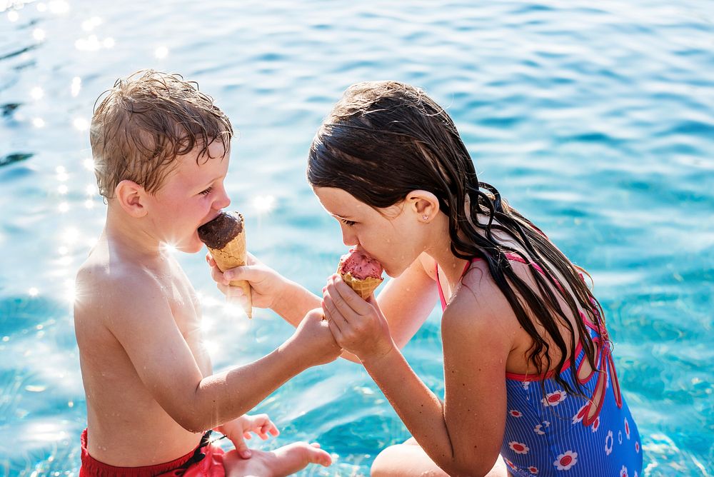 Kids sharing ice creams by the pool