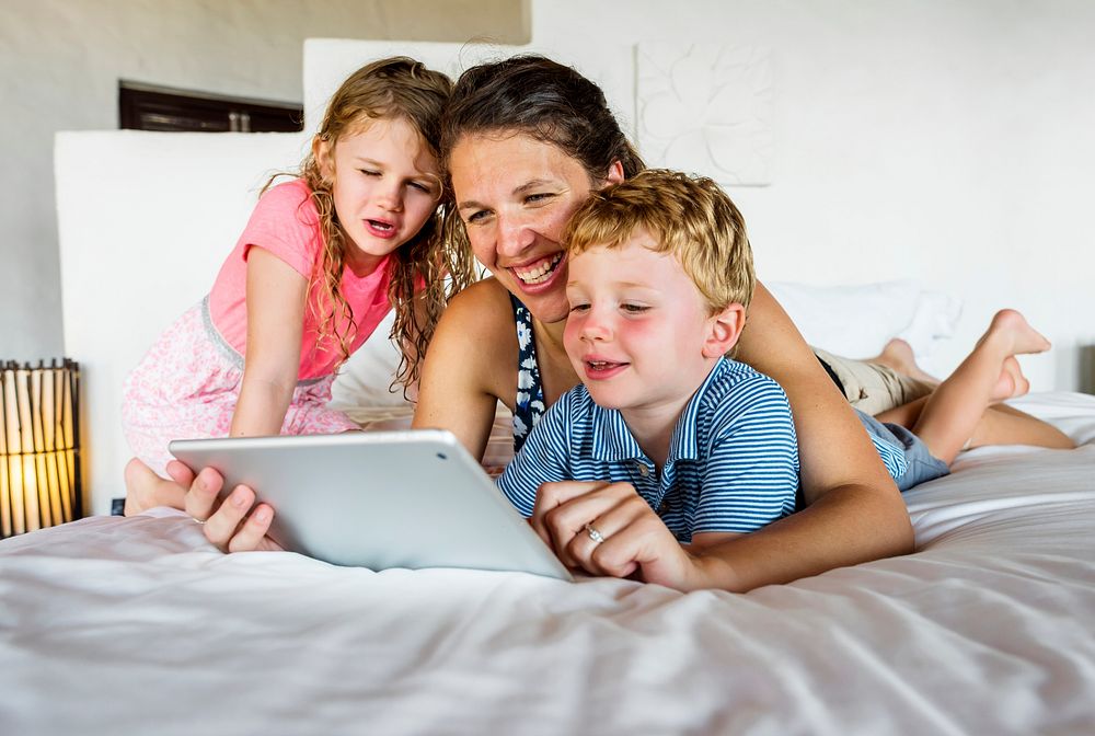 Mother on bed with children using tablet
