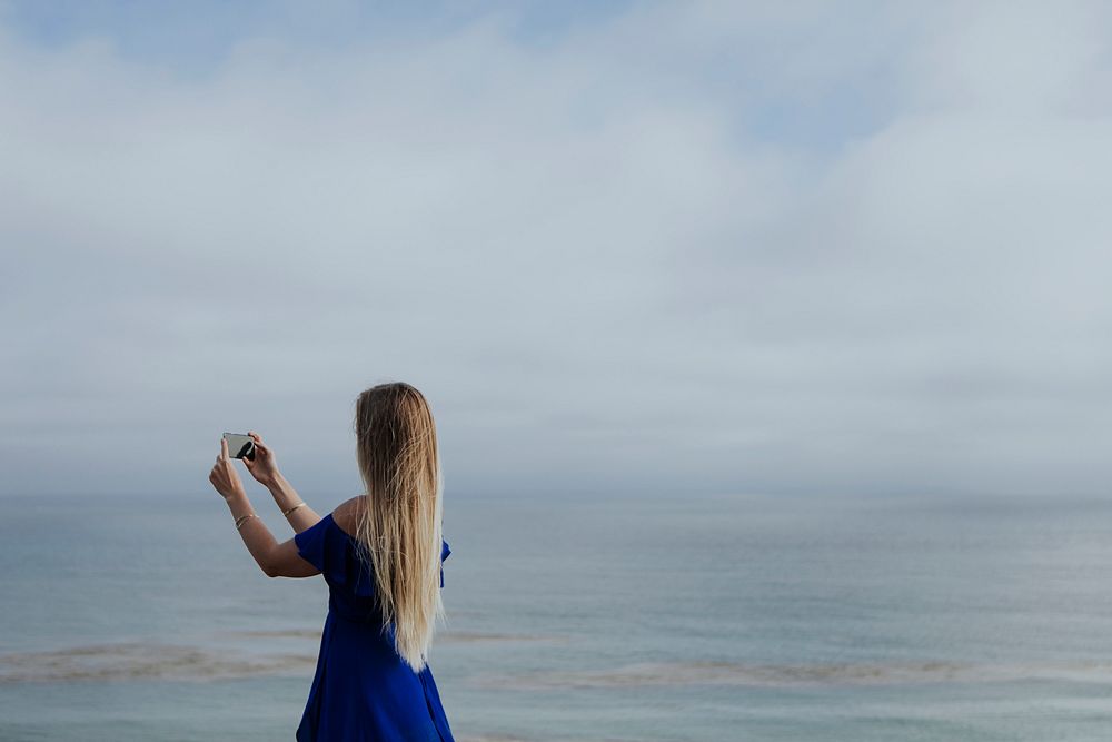 Blonde woman taking a photo with her phone