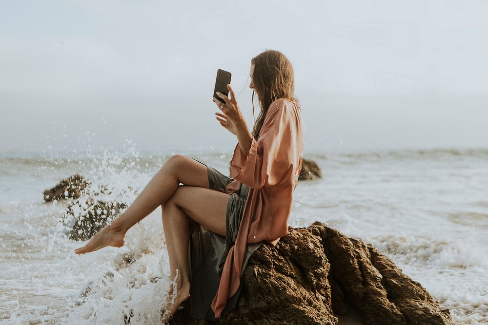 Woman taking photos with her phone on the beach