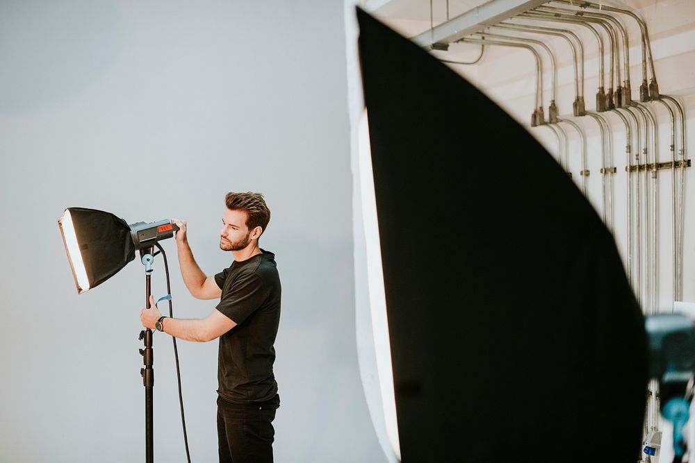 Young man adjusting the soft box in a studio