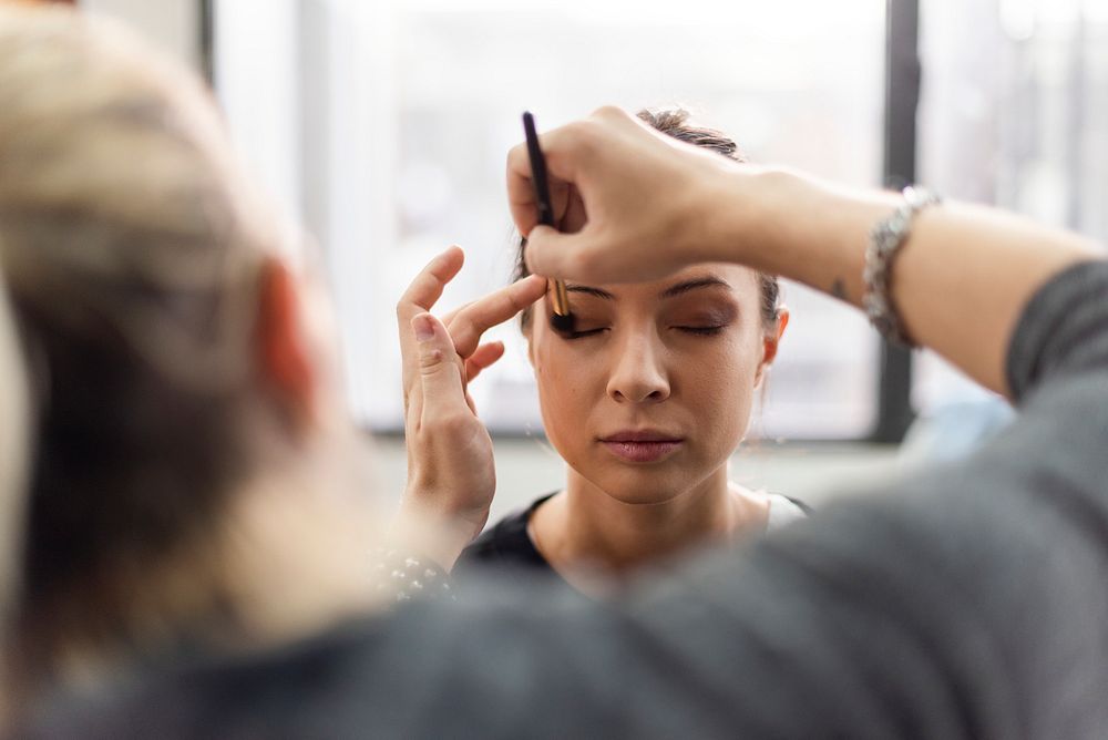 Makeup artist applying eyeshadow onto model
