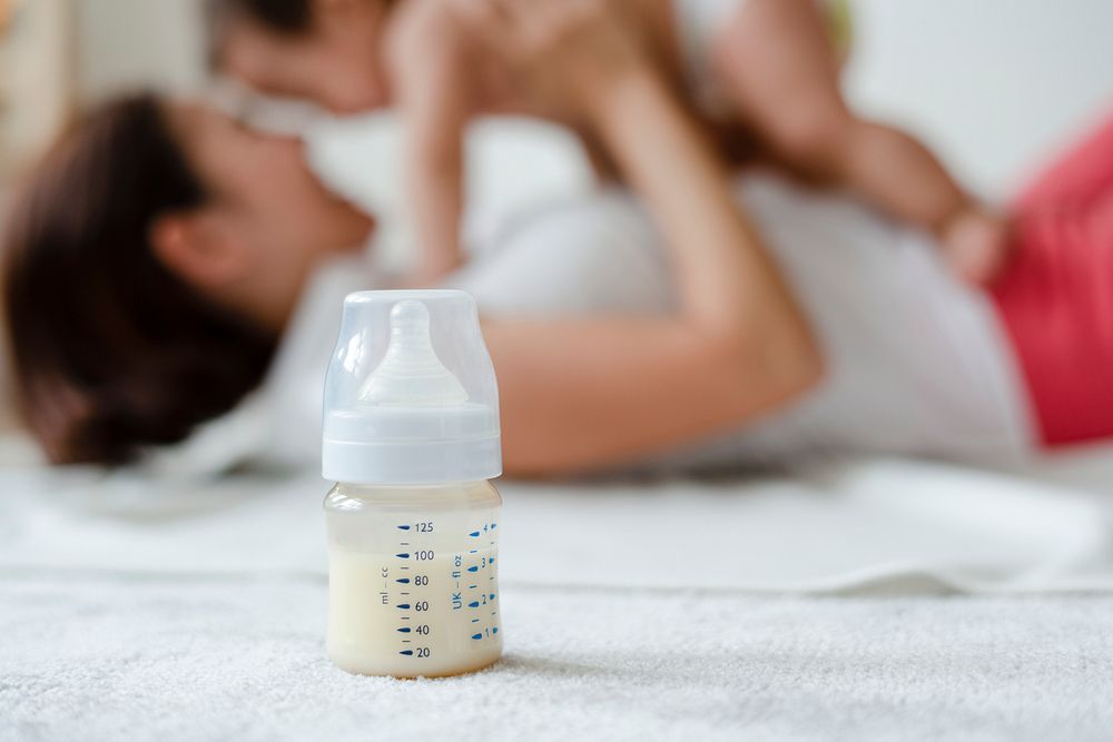 Baby formula with mom and baby in the background
