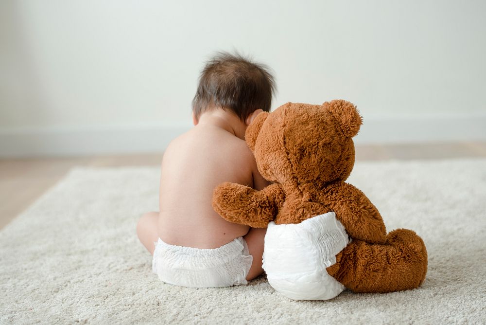 Back of a baby with a teddy bear