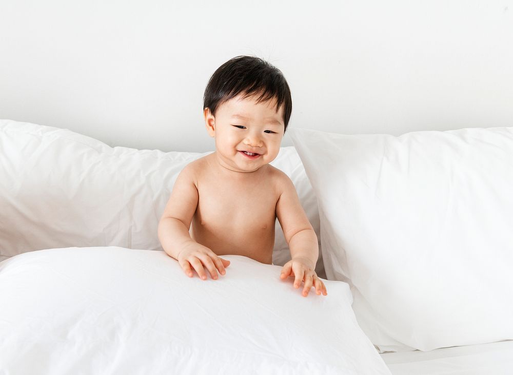 Cheerful baby sitting on the bed