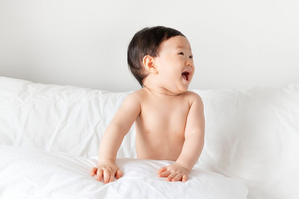 Cheerful baby sitting on the bed