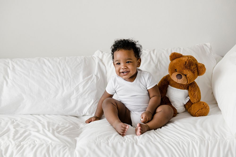 Baby with a teddy bear on the bed