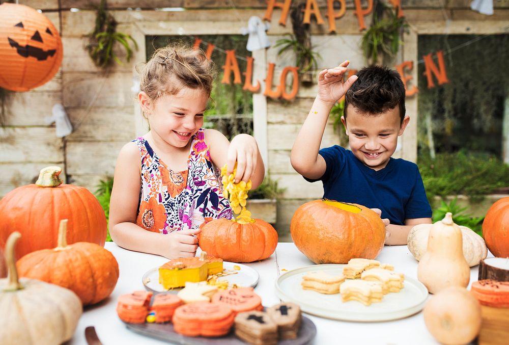 Young kids carving Halloween jack-o'-lanterns