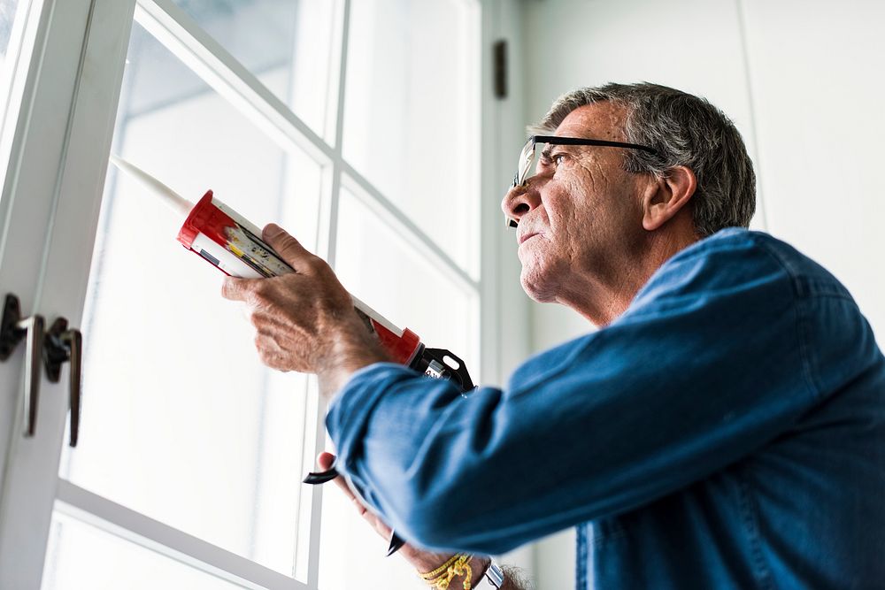 Man using a silicone gun to repair a window