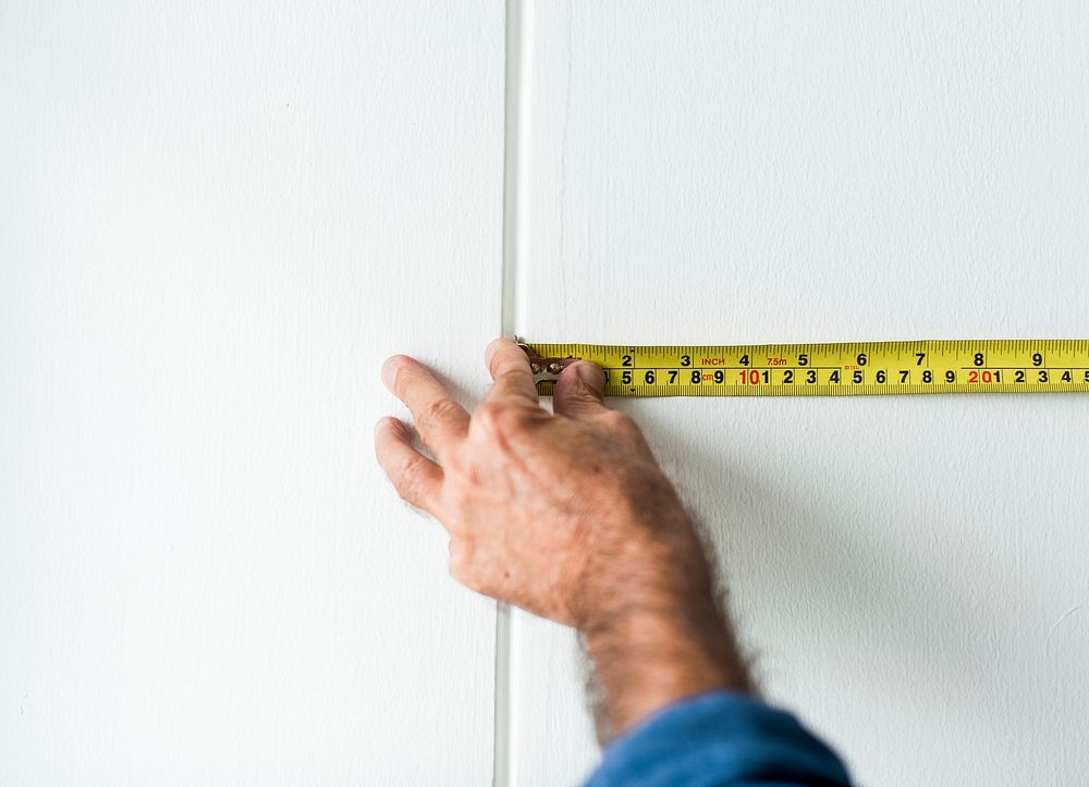 Man measuring the wall with a measuring tape