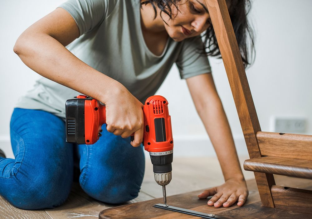 Woman using hand drill to assemble a wooden table
