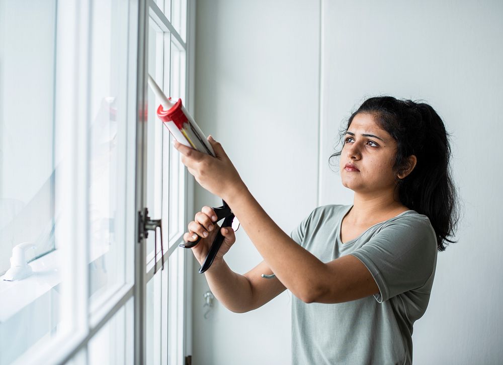 Woman using a silicone gun to repair a window