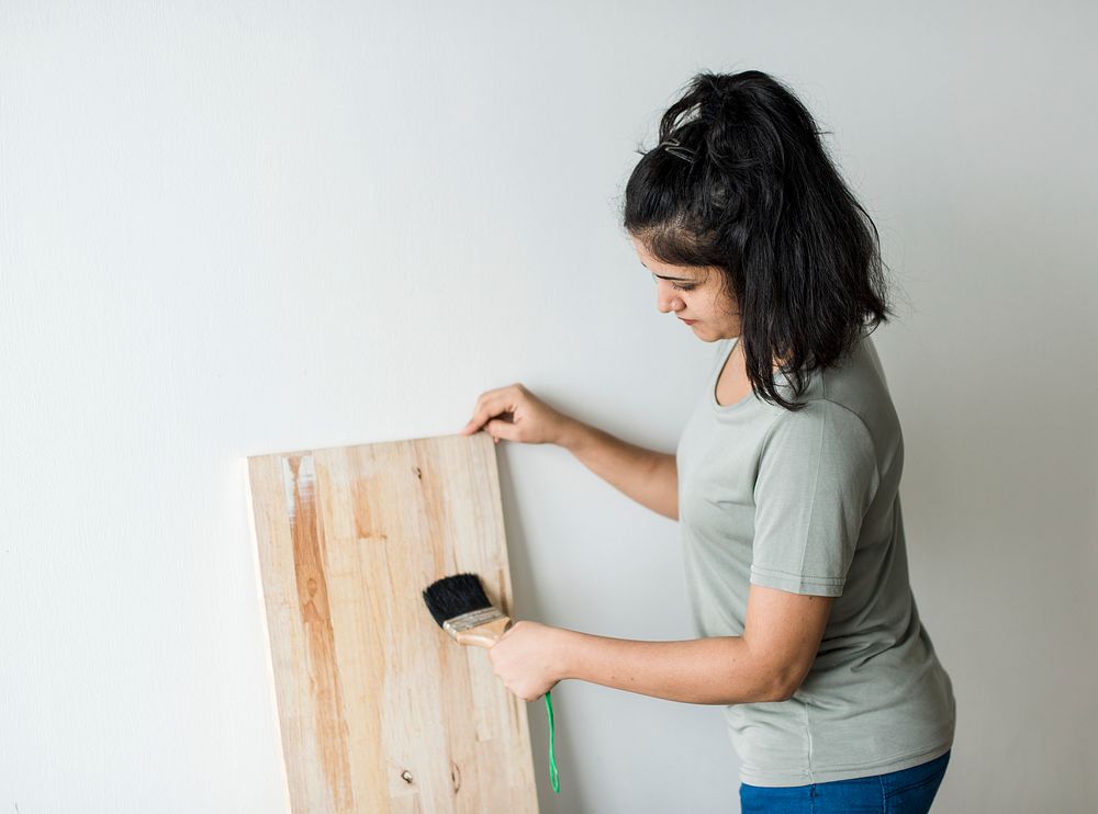Woman coating a wooden plank with lacquer