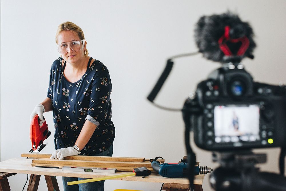 Female blogger ​​​​​​​​​​​​​​cutting a plank with a jigsaw machine