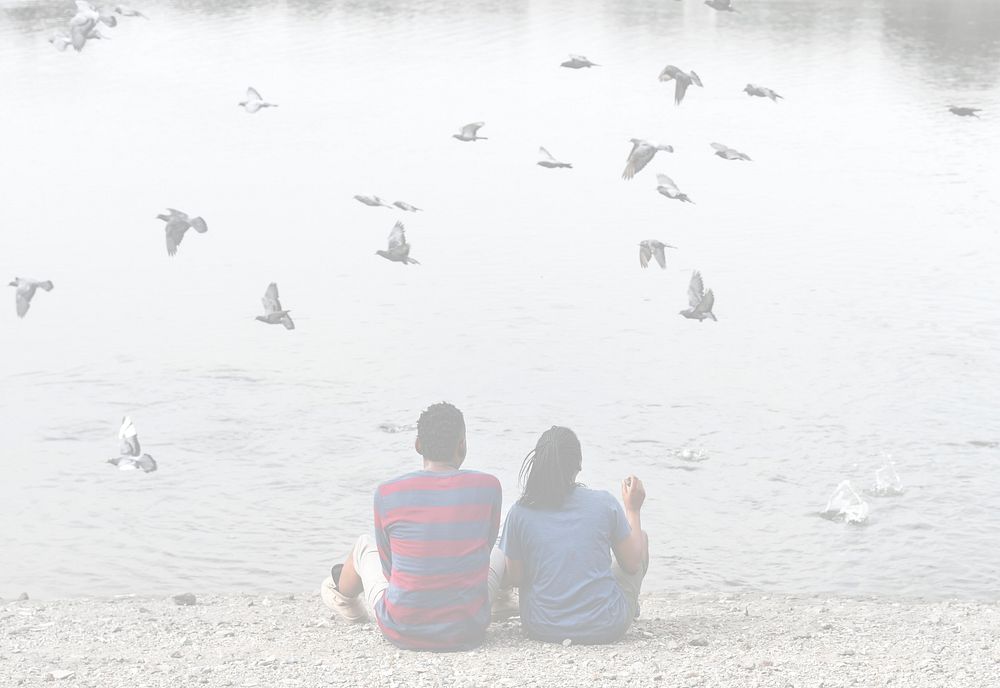 Couple sitting by the lake with birds flying