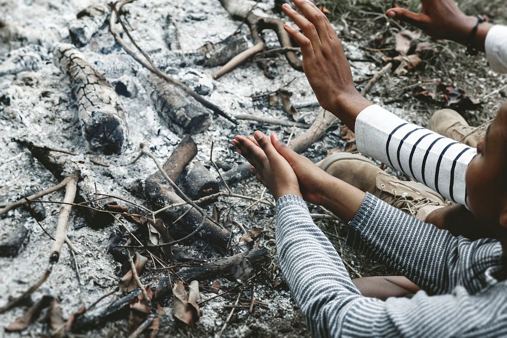 Warming hands by the campfire ashes