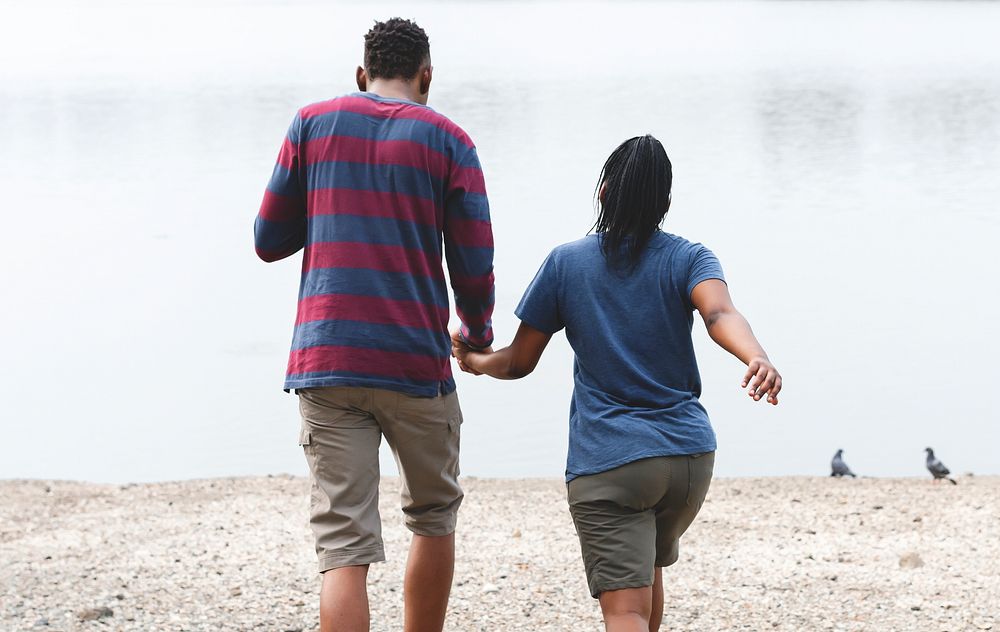 Cheerful couple holding hands by the lake