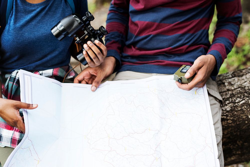 Trekking couple using map and compass in a forest