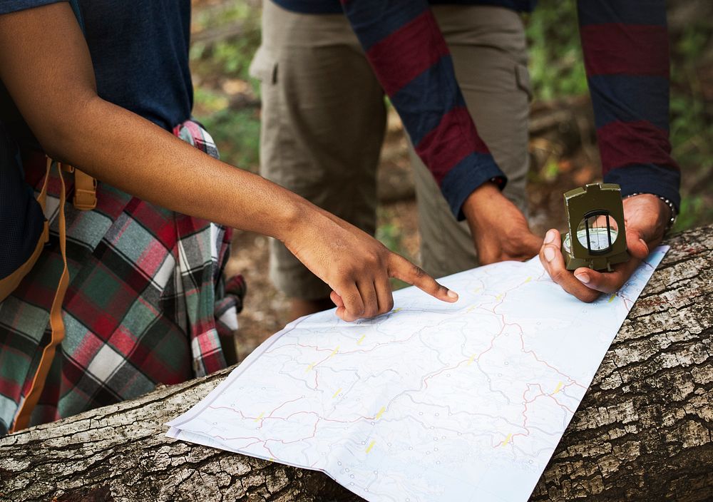 Trekking couple using map and compass in a forest