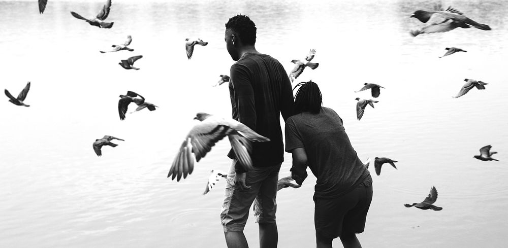 Couple and pigeons by the lake