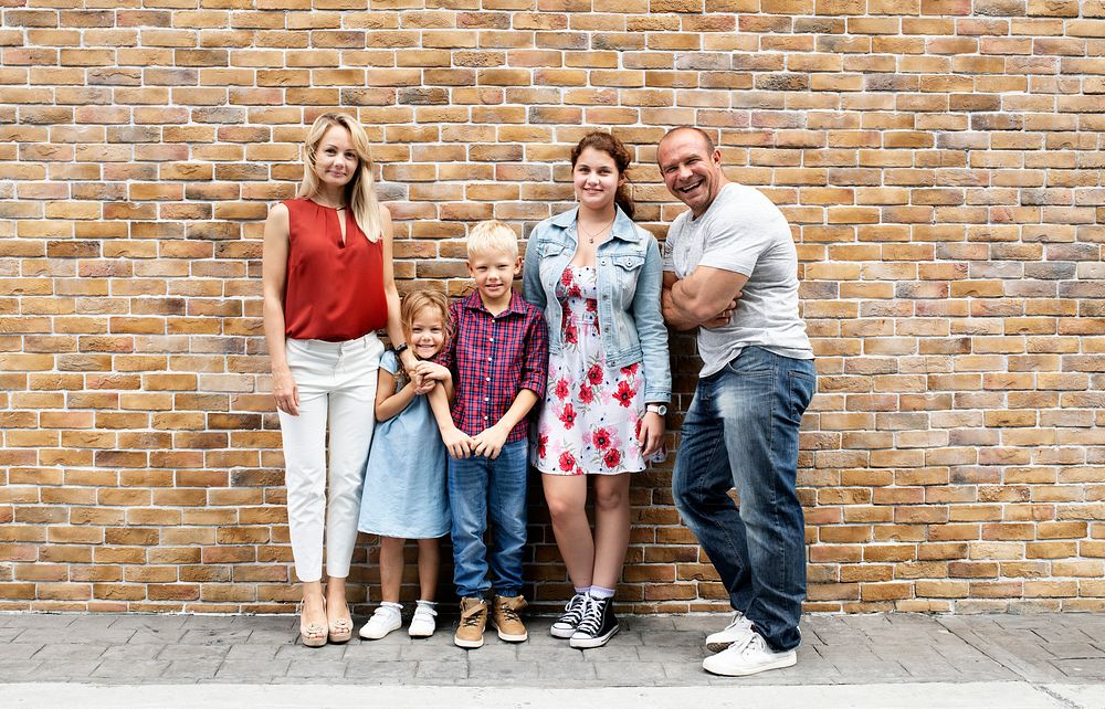 Cheerful family standing by a brick wall