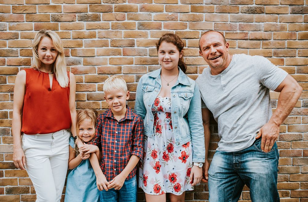 Cheerful family standing by a brick wall