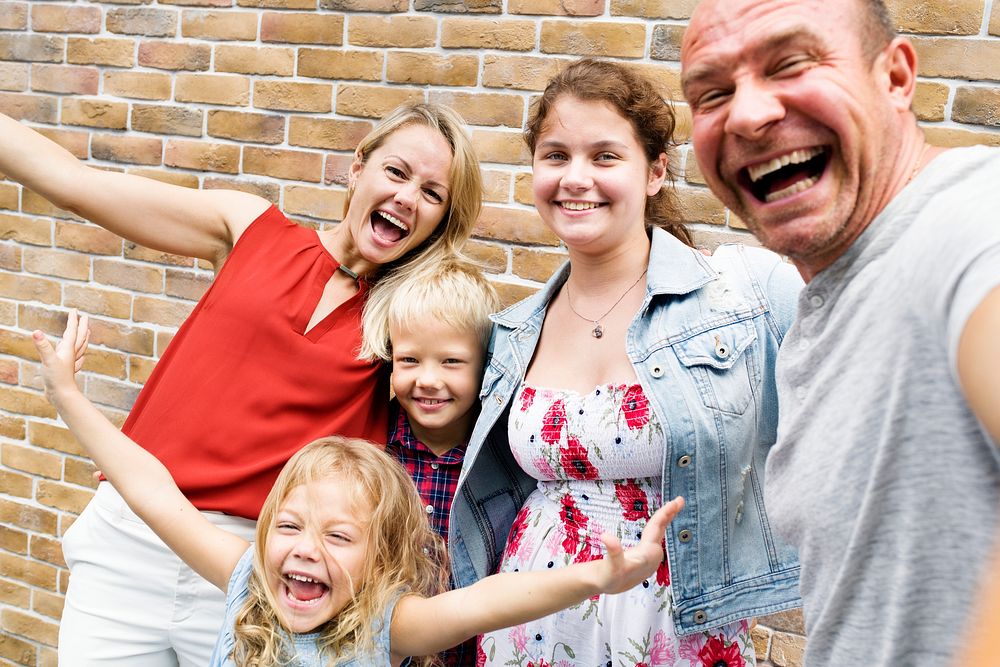 Cheerful family taking a selfie by a brick wall