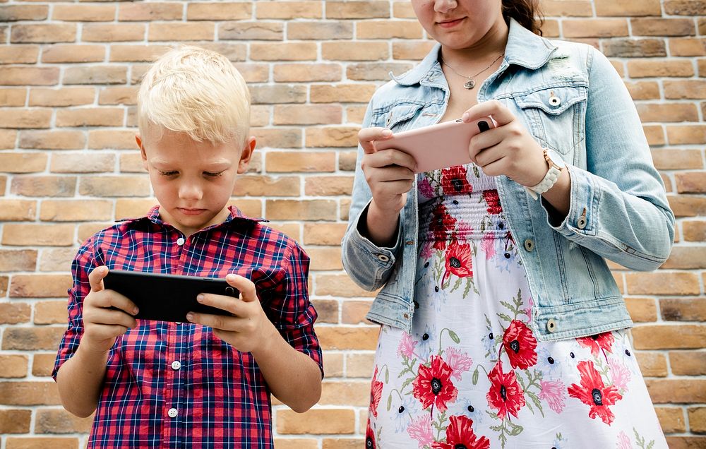 Young boy playing a mobile game against his sister