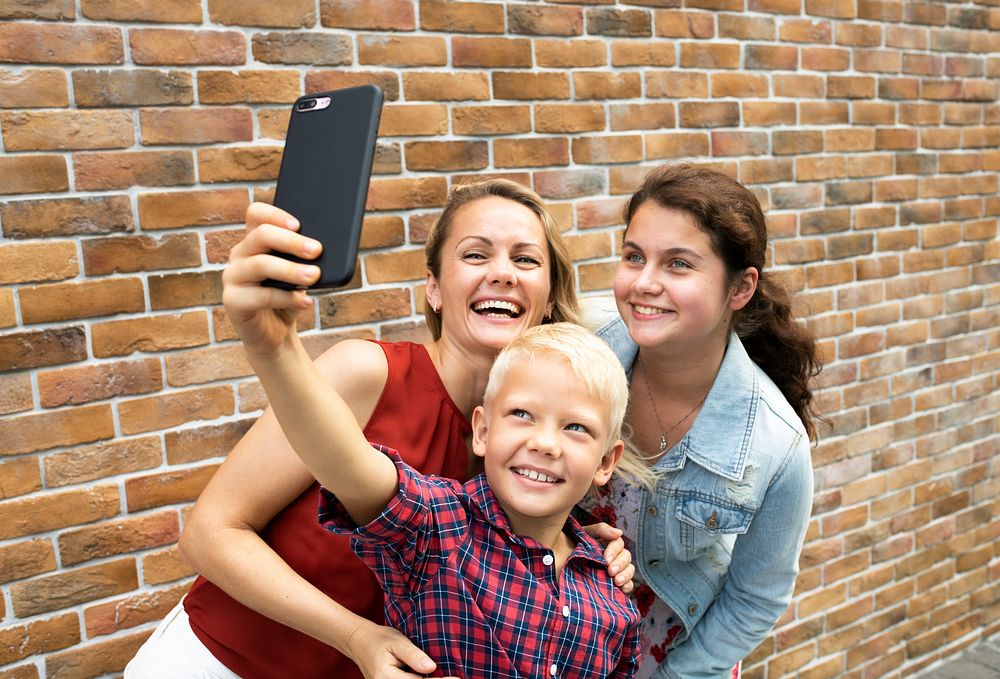 Young boy taking a selfie with his mom and sister