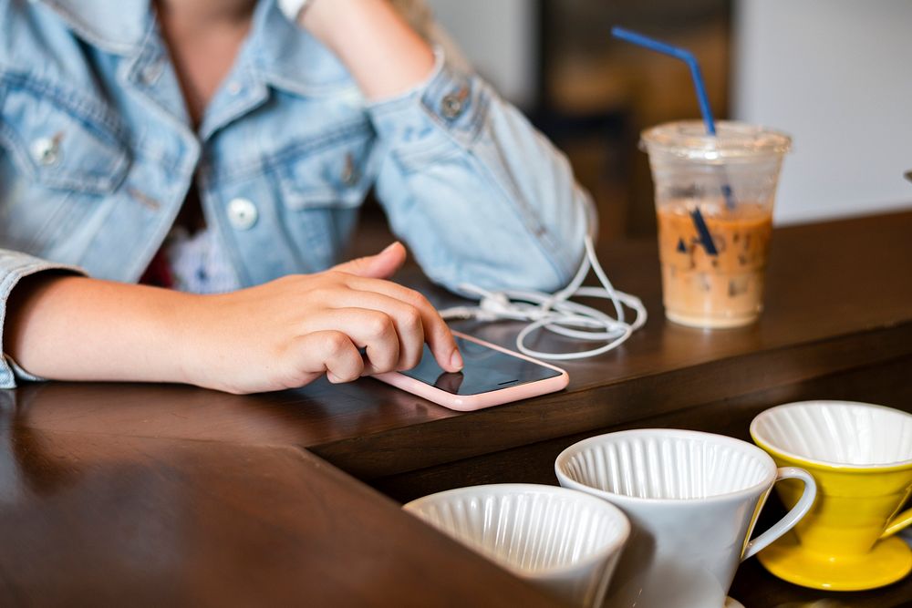 Teen girl playing on her phone at a cafe