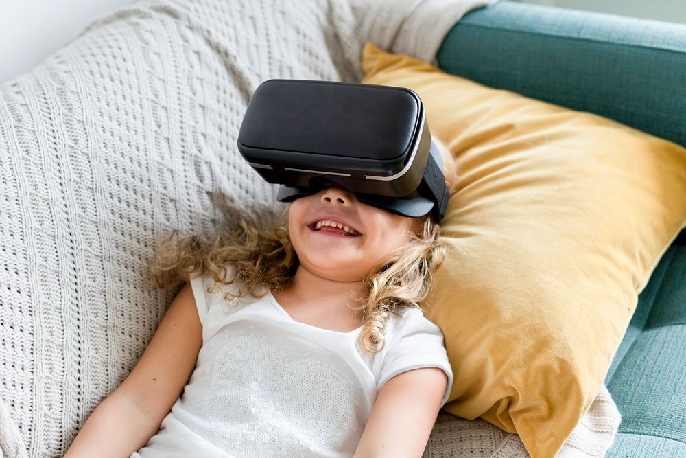 Little girl watching a movie through VR goggles