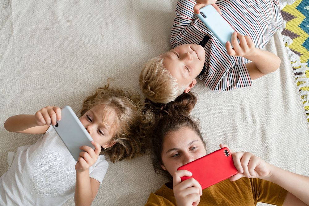 Kids lying on the floor and playing games on their phones