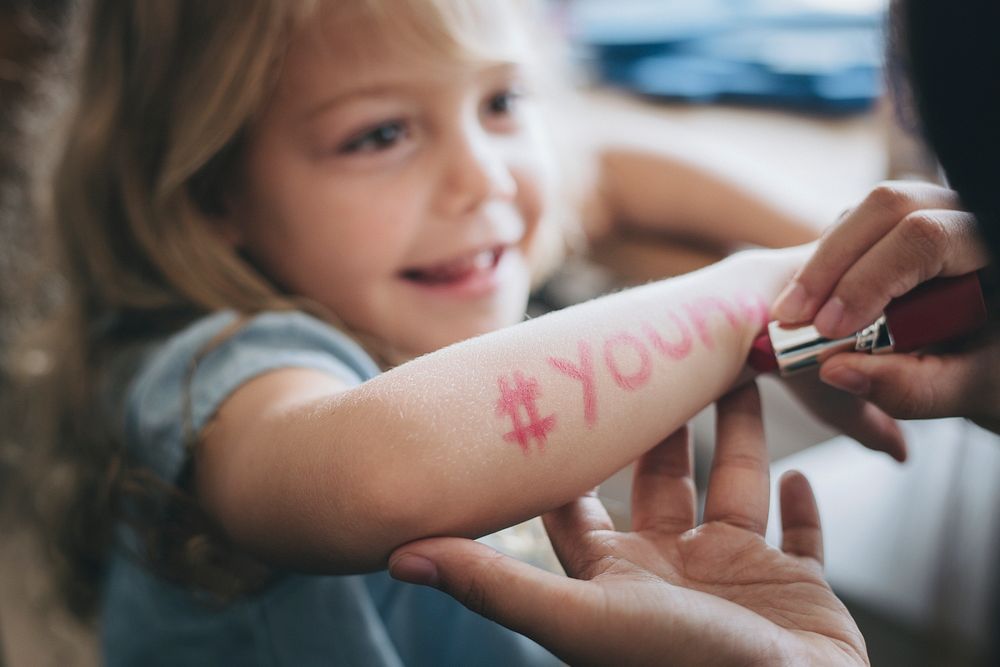 Little girl with hashtag young written on her arm