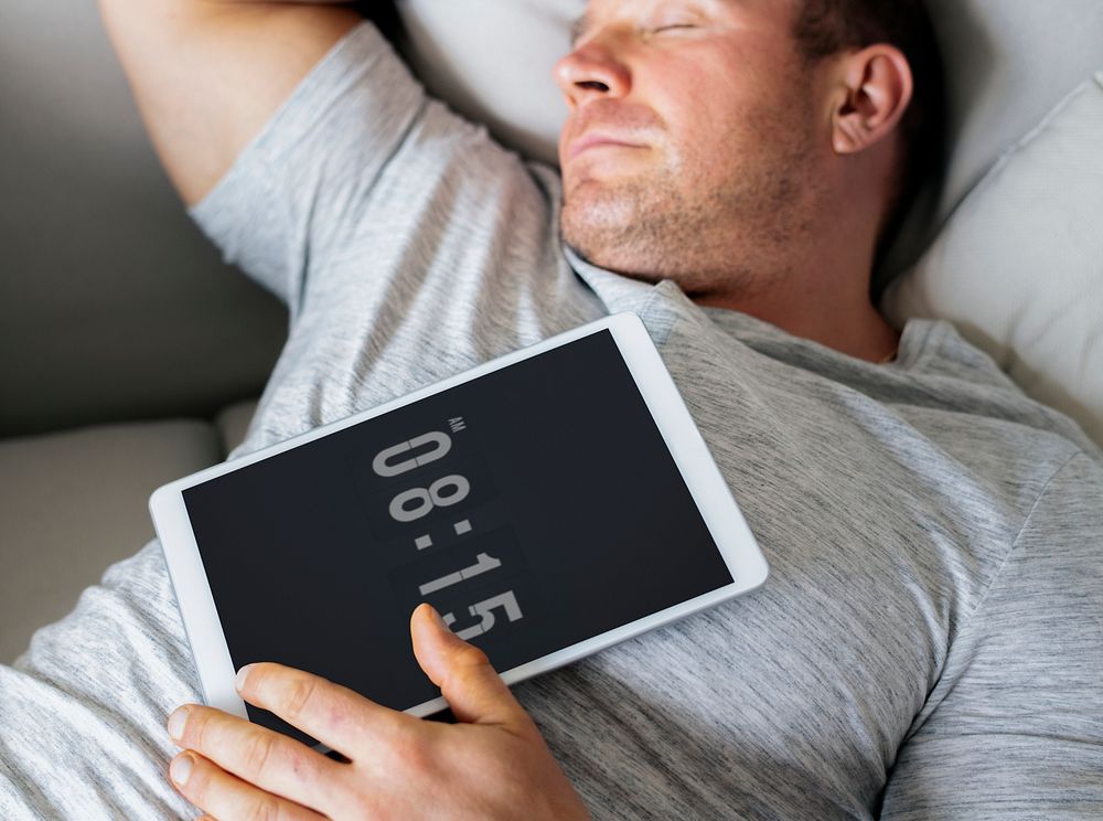 Man asleep on the sofa with his tablet on his chest