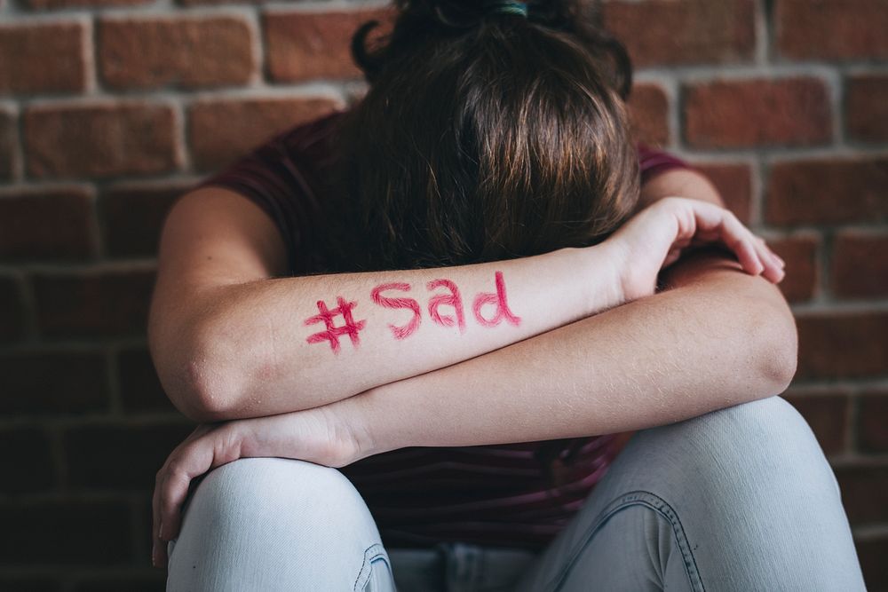 Girl with hashtag sad written on her arm