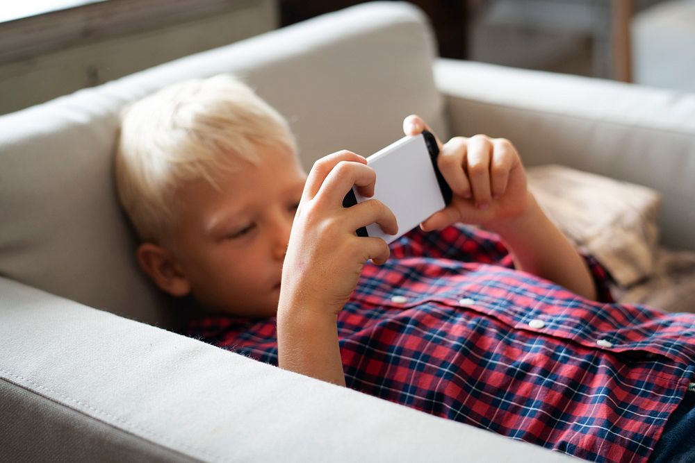 Boy playing on his phone on the sofa