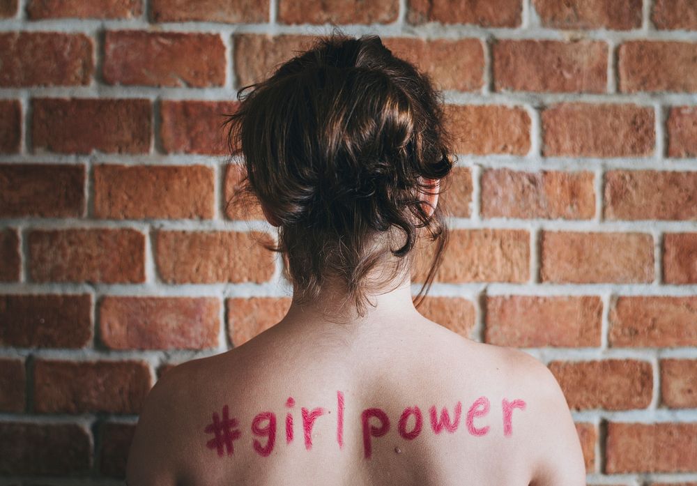 Girl with hashtag girl power written on her back