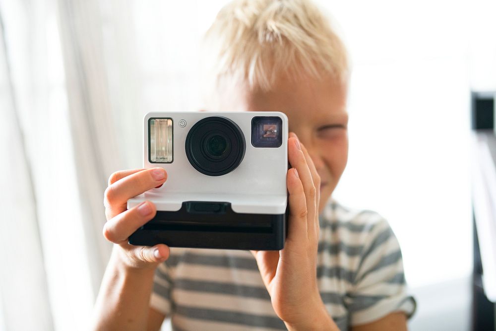 Blond boy taking an instant photo