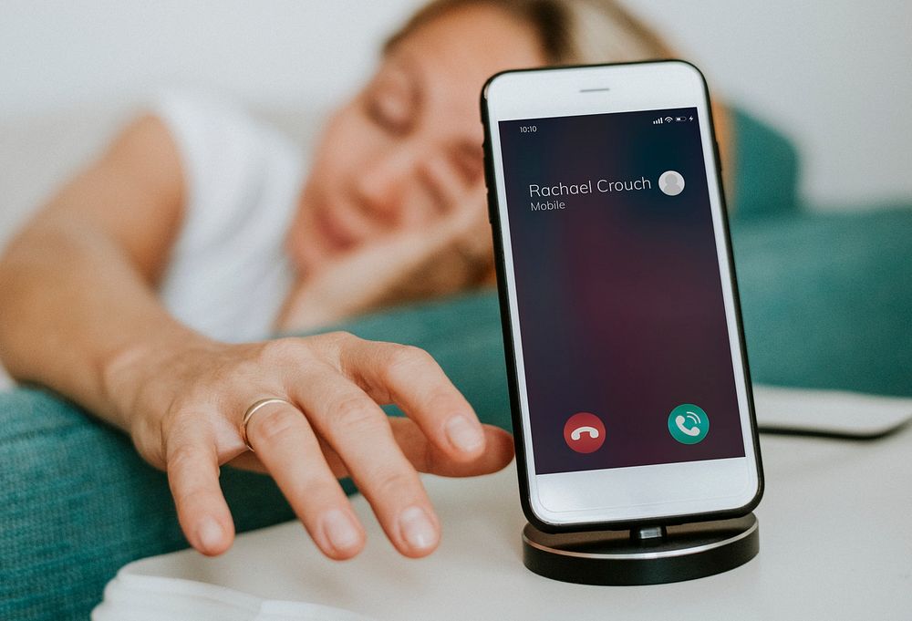 Drowsy woman reaching for her phone to turn off the alarm