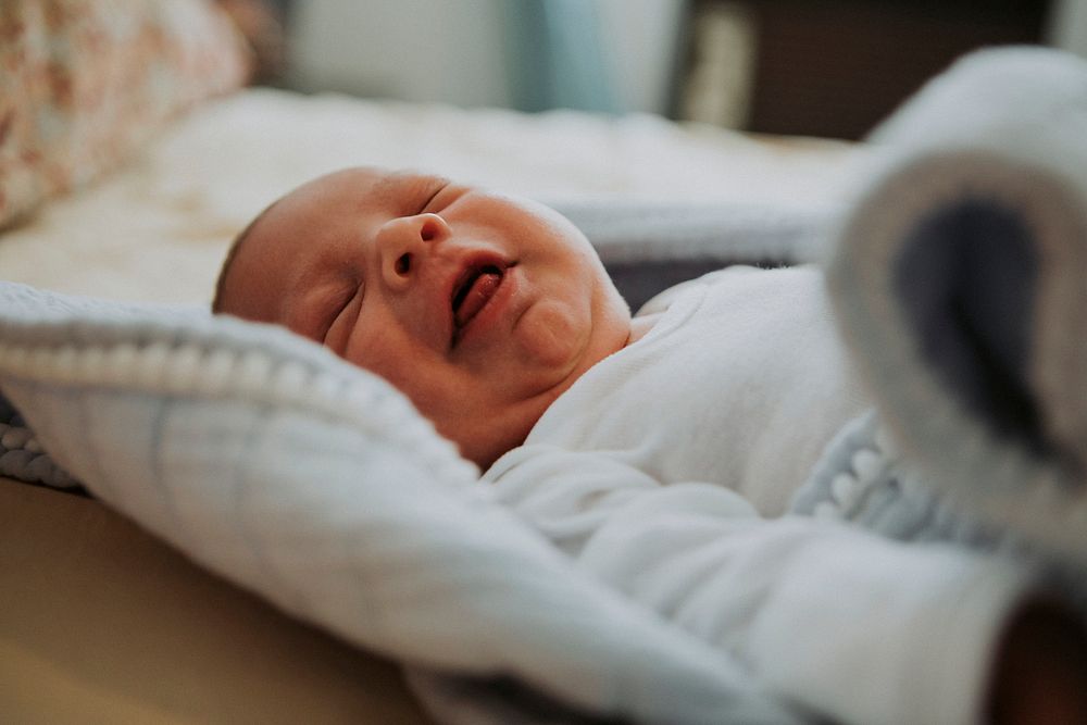 Infant baby on a bed yawning